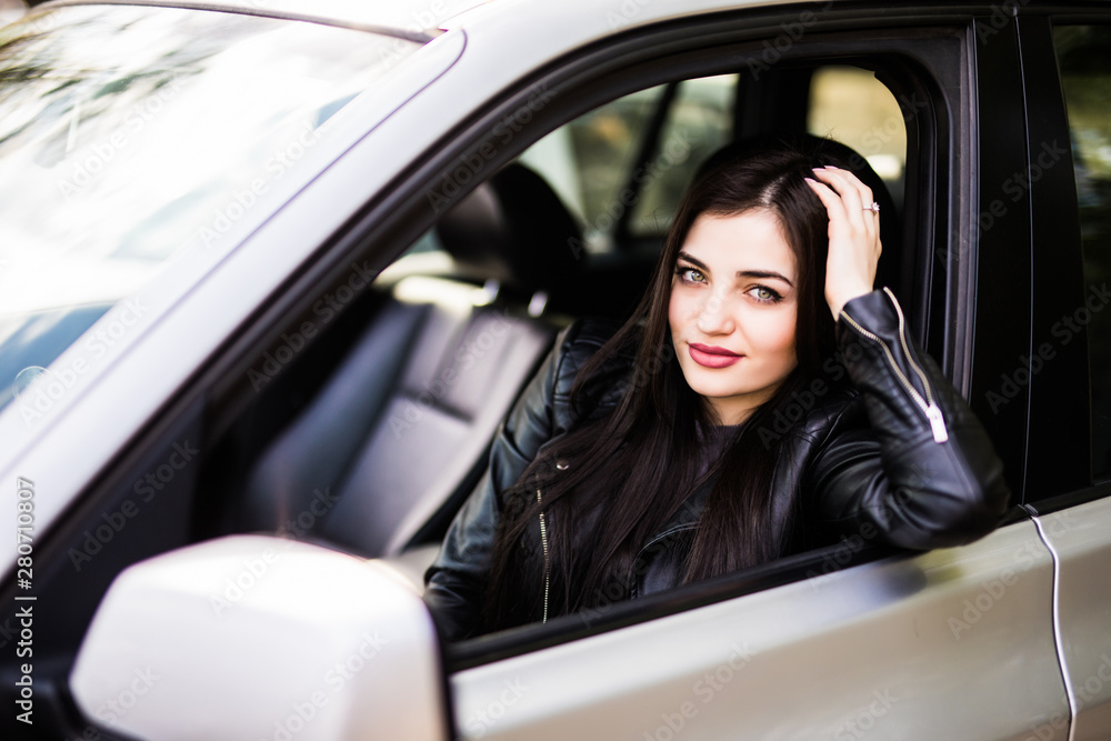 Portrait of young woman sitting in the car looking out the window, leaning on the arm