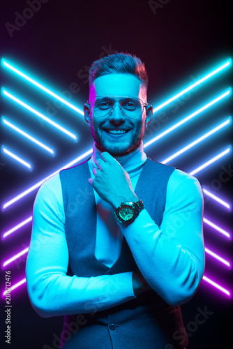 Young handsome model posing in a studio in a trendy neon light. Fashionable man in a stylish suit. Vibrant color. Bright colorful light effects. Disco style. Overlay. Gel filter. Supersaturated