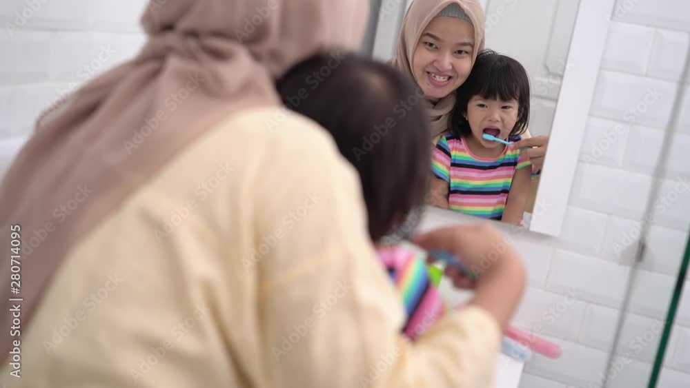 muslim mother and her daughter brushing teeth together before bed muslim mother and her daughter brushing teeth together before bed