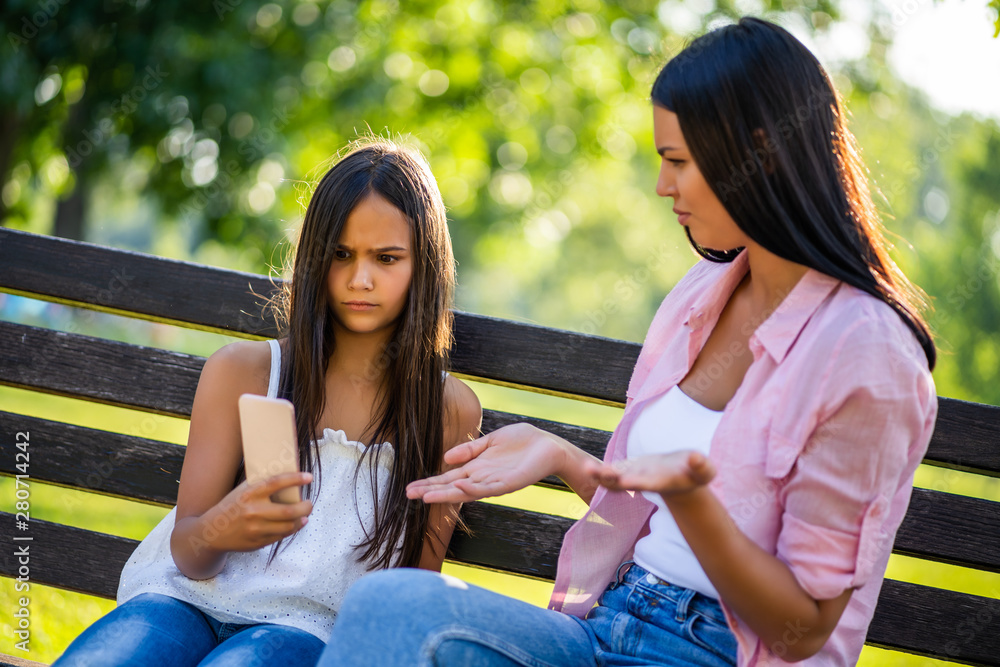 Family having nice time in park together. They are using smartphone. Family having nice time in park together. They are using smartphone.
