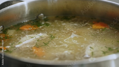 Boiling pot of soup with carrots and herbs
