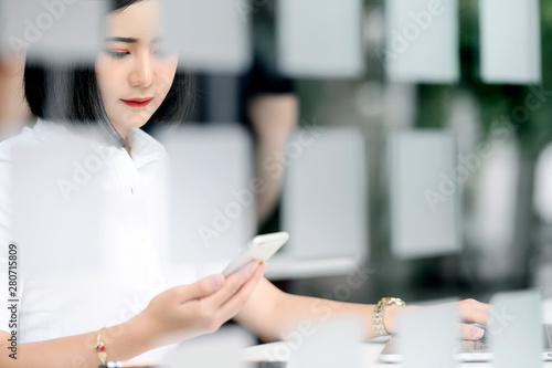 Portrait of beautiful woman using smartphone while sitting in modern office.