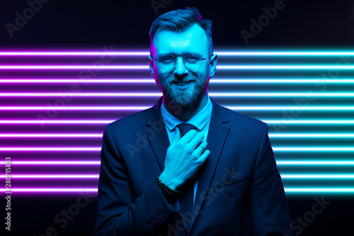 Young handsome model posing in a studio in a trendy neon light. Fashionable man in a stylish suit. Vibrant color. Bright colorful light effects. Disco style. Overlay. Gel filter. Supersaturated