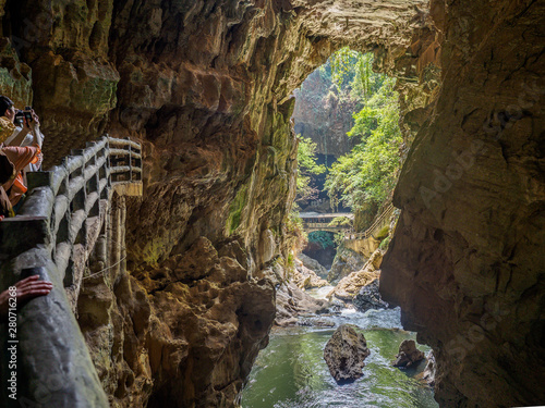 Small path at the entry of the "Jiu Xiang Rong Dong" cave near Kunming (China) with view to the outside alongside a small river.