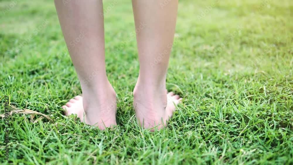 Girl walking with barefoot on green grass with sunlight, slow motion. Girl walking with barefoot on green grass with sunlight, slow motion.