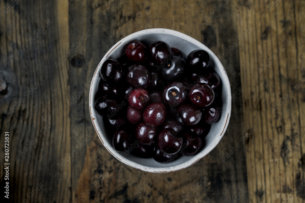 fresh organic ripe black cherries in a white bowl on a rustic wooden table fresh organic ripe black cherries in a white bowl on a rustic wooden table
