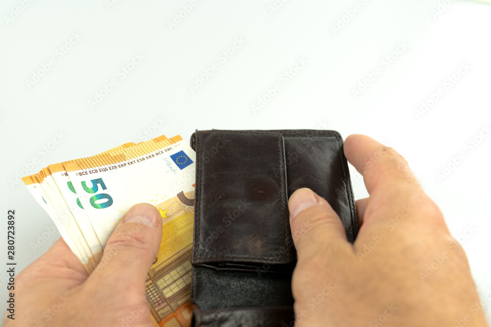 man taking fifty Euro banknotes out of a brown leather wallet man taking fifty Euro banknotes out of a brown leather wallet