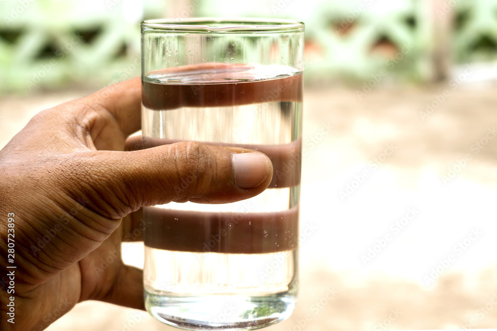 A glass of pure clean mineral water in hand isolated on natural background A glass of pure clean mineral water in hand isolated on natural background