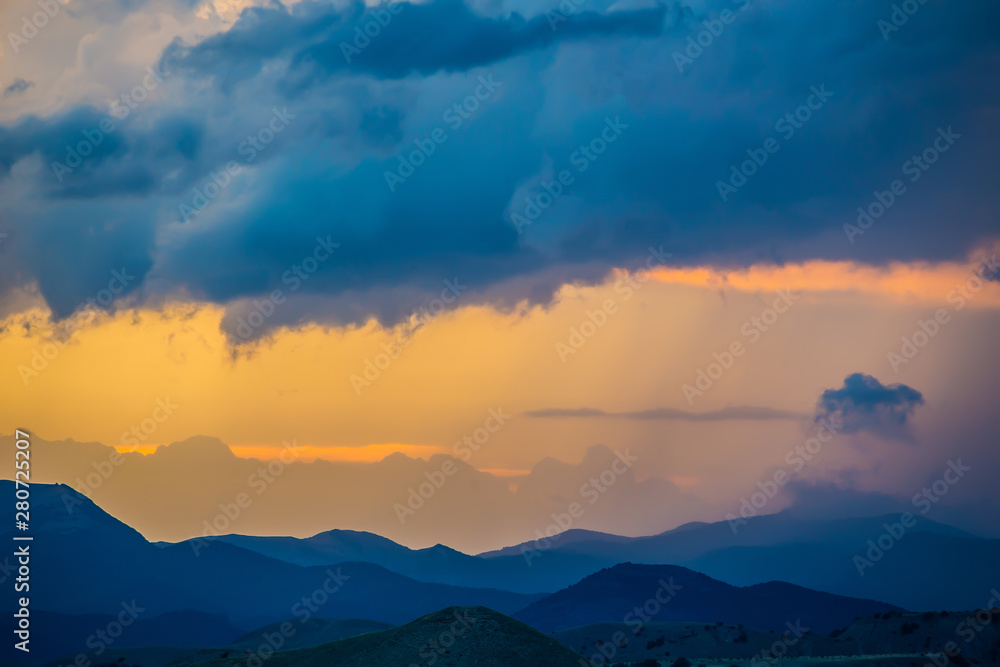 sunset in the cloudy sky over the mountains
