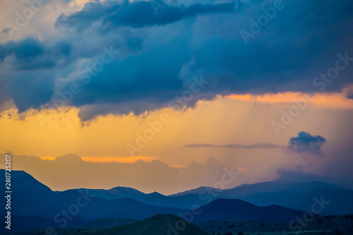 sunset in the cloudy sky over the mountains