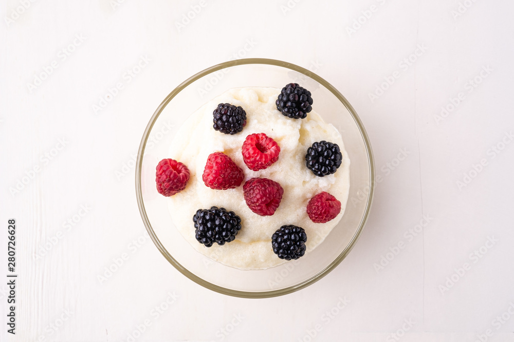 Semolina pudding porridge dessert with blackberry and raspberry berries in glass bowl, breakfast, white wooden background, isolated Semolina pudding porridge dessert with blackberry and raspberry berries in glass bowl, breakfast, white wooden background, isolated