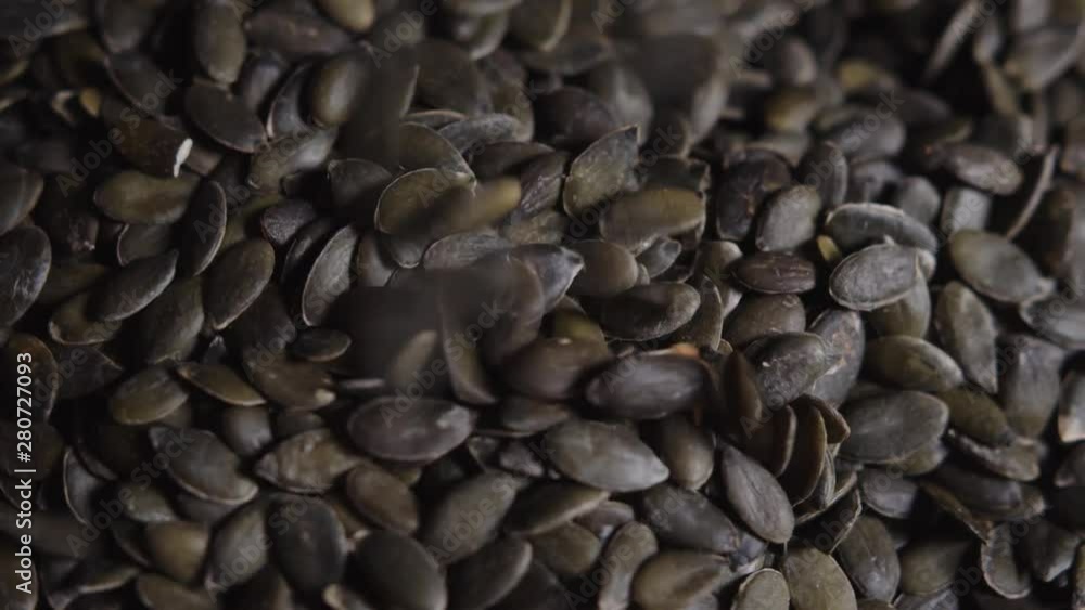 Close up of shelled pumpkin seeds rotating with some falling down. Static. Top view Close up of shelled pumpkin seeds rotating with some falling down. Static. Top view