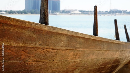 old wooden fisher boat by blue sky and city