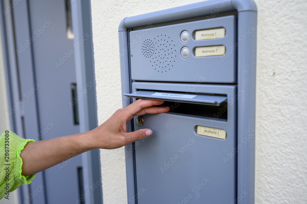 Frau öffnet einen Briefkasten am Haus Frau öffnet einen Briefkasten am Haus