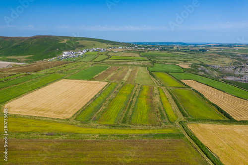 Aerial view of green fields and the ocean in Rhossili on the Gower Peninsula, Wales