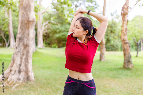 Side view of happy young athlete woman stretching her upper arm bicep before and after her morning exercise at a public park