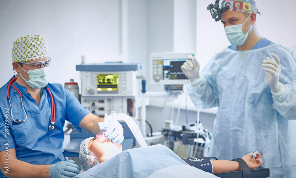 Several doctors surrounding patient on operation table during t Several doctors surrounding patient on operation table during t