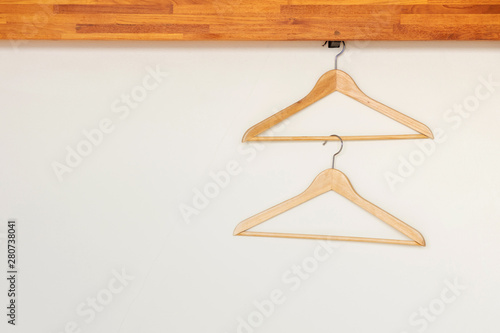 Wooden clothes hangers on minimal open closet storage with copy space on wall background.
