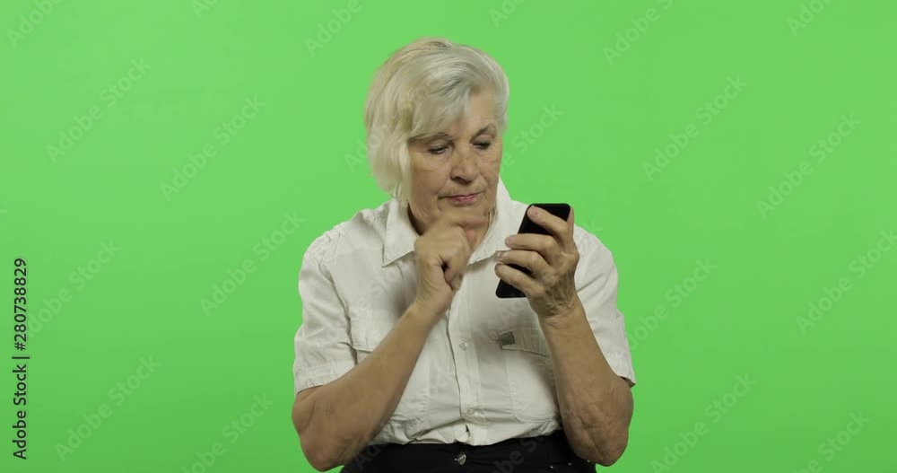 An elderly woman works on a smartphone. Old grandmother smiles. Chroma key An elderly woman works on a smartphone. Old grandmother smiles. Chroma key