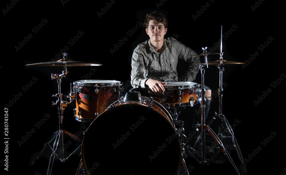 Fototapeta premium Professional drummer playing on drum set on stage on the black background
