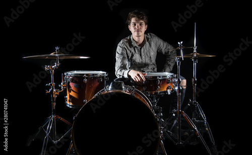 Billede på lærred Professional drummer playing on drum set on stage on the black background