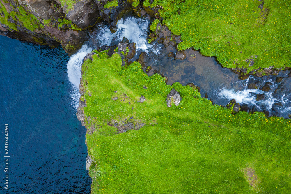 Aerial view of Mulafossur waterfall in Gasadalur village in Faroe Islands, North Atlantic Ocean. Photo made by drone from above. Nordic Natural Landscape.