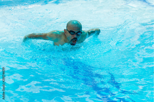 Bald and mustache man swimming breaststroke in the pool. swimmer is training in the pool using breaststroke technique.