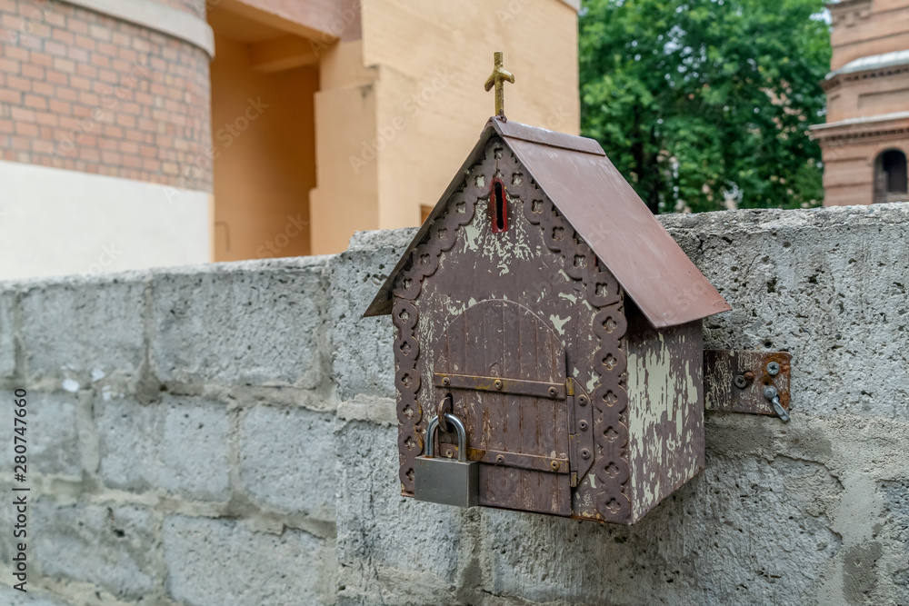 Toy house, a place for donations, attached to a stone fence close-up