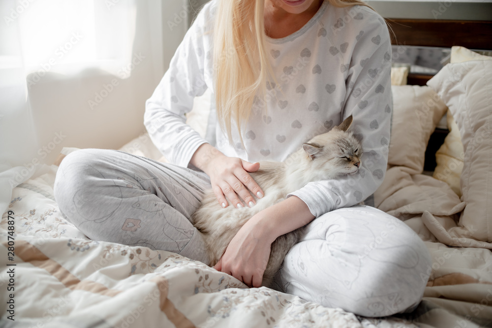 Blonde Giirl hygge with fluffy cat, pajama and blanket. Hugge and lagom concept comfort and simple life . Horizontal copyspace