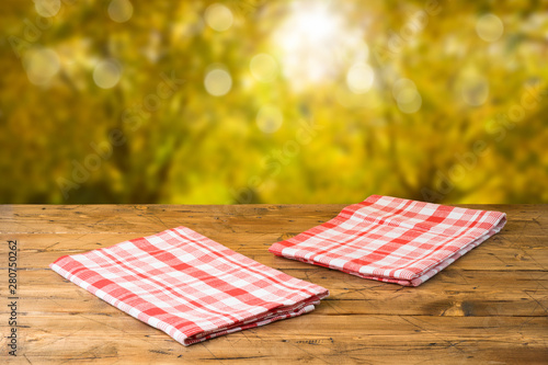 Empty wooden table with tablecloth over autumn nature park background