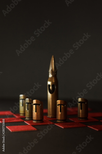 A hand-crafted chess pieces made of bullet shells (7.62x54 mm and 7.62x39 mm caliber). Chess game. Pawns guard the king. Dark background. The small depth of field photo