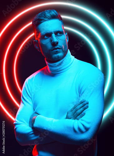 Young handsome model posing in a studio in a trendy neon light. Fashionable man in a stylish suit. Vibrant color. Bright colorful light effects. Disco style. Overlay. Gel filter. Supersaturated