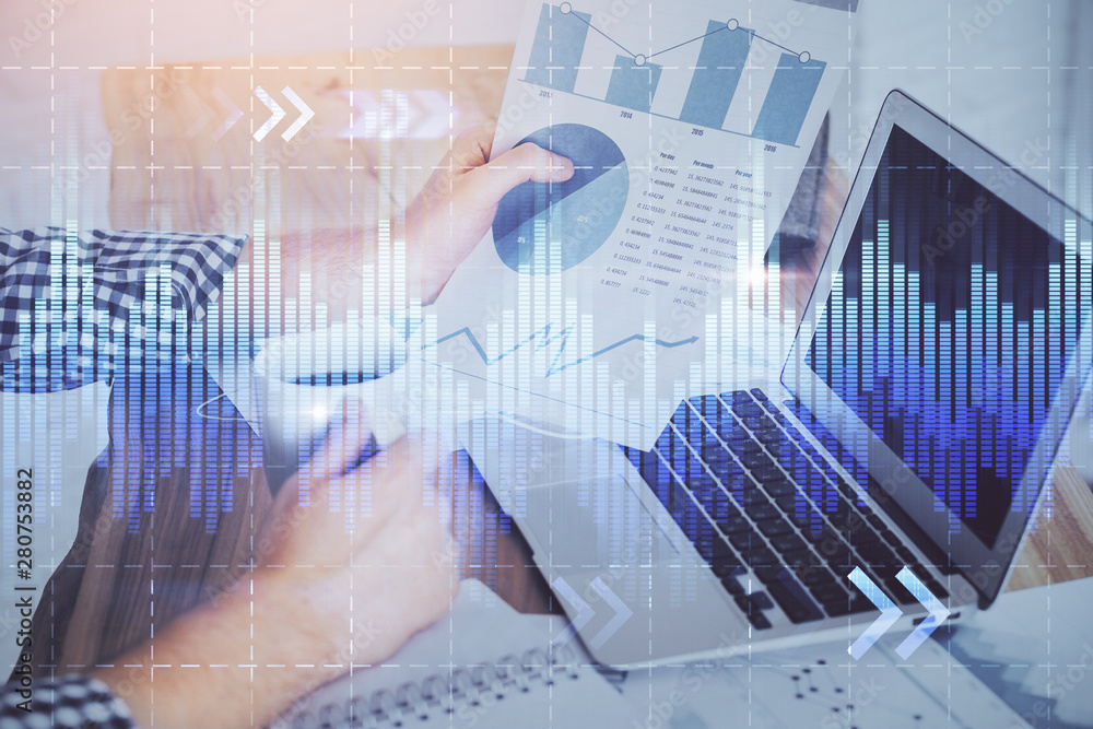 Obraz premium Stock graph with businessman typing on computer in office on background. Concept of analysis. Double exposure.