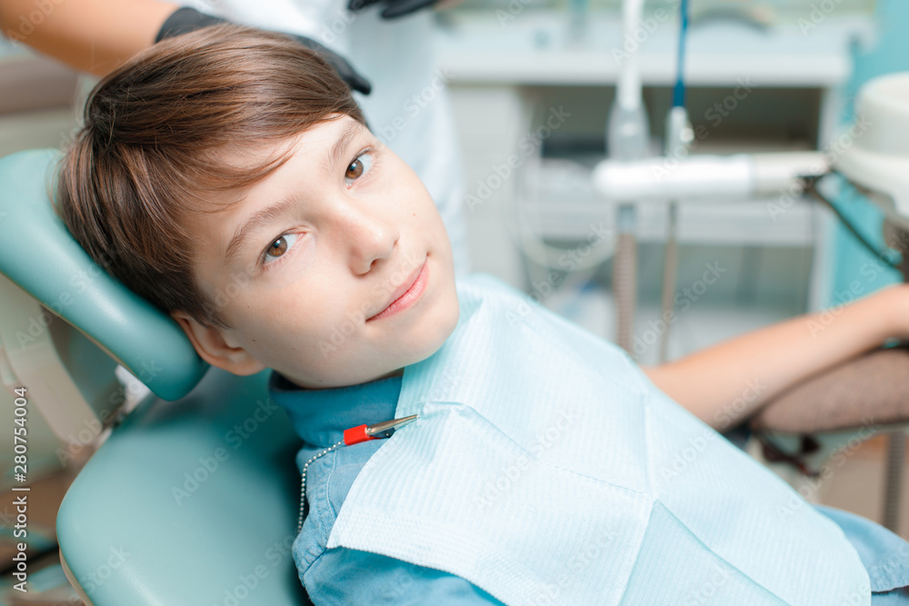 Patient in dental chair. Little boy having dental treatment at dentist's office. Healthy teeth, dental care concept.