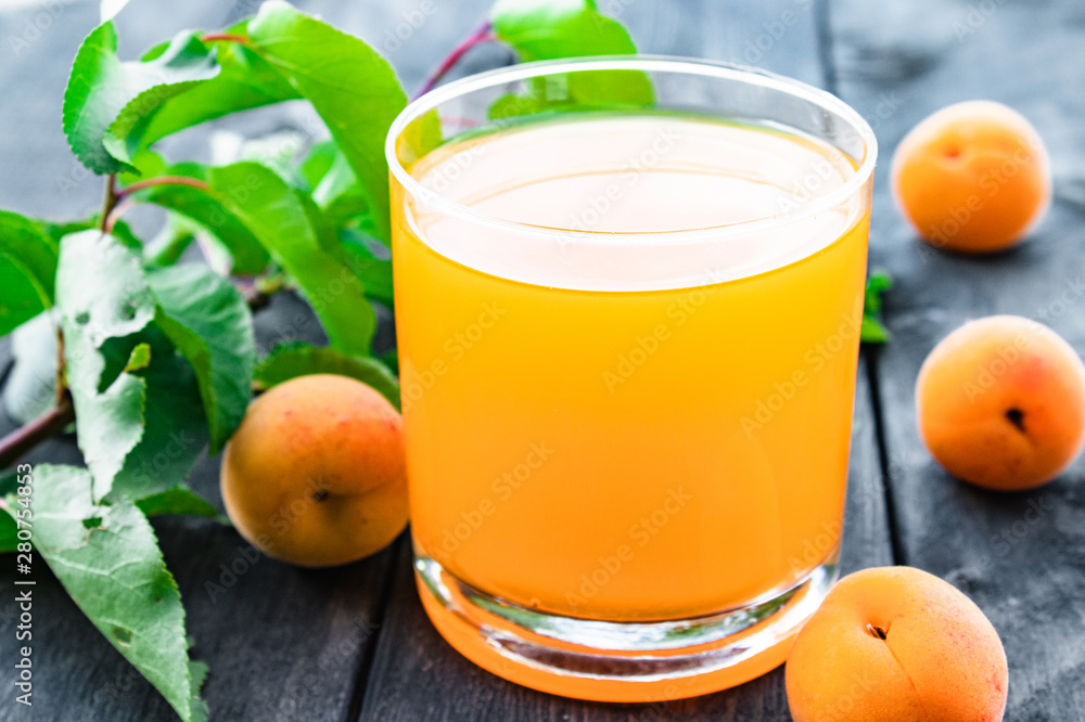 Fresh apricot juice with apricots and a branch with green leaves on the background of old boards. Fresh apricot juice with apricots and a branch with green leaves on the background of old boards.