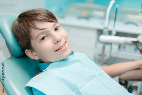 Little boy in dental chair. Smiling and satisfied patient at dentist's office after treatment. Healthy teeth, dental care concept.