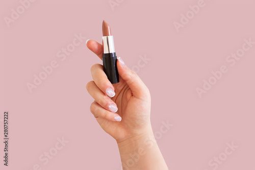  Woman hand holding lipstick. Make up products.
