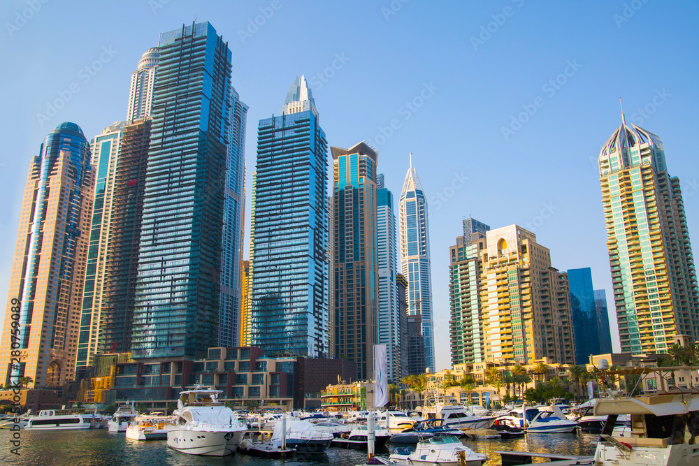 Fototapeta premium Dubai, UAE United Arabs Emirates. Dubai marina skyscrapers and yachts at sunset. Apartments, hotels and office buildings, modern residential development of UAE