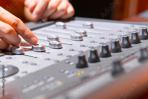 sound engineer hands mixing audio track on digital mixer in recording studio. music production, broadcasting concept