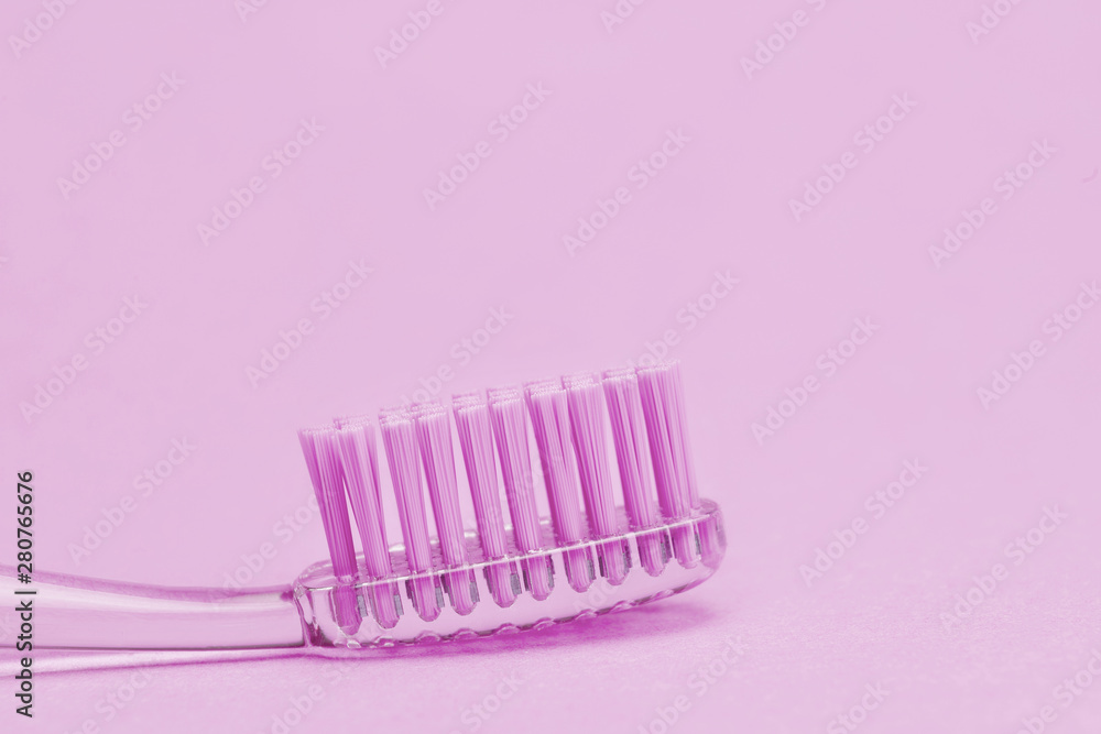 Close up view of transparent toothbrush with purple bristles on color background. Healthy teeth, dental care concept. Space for text.