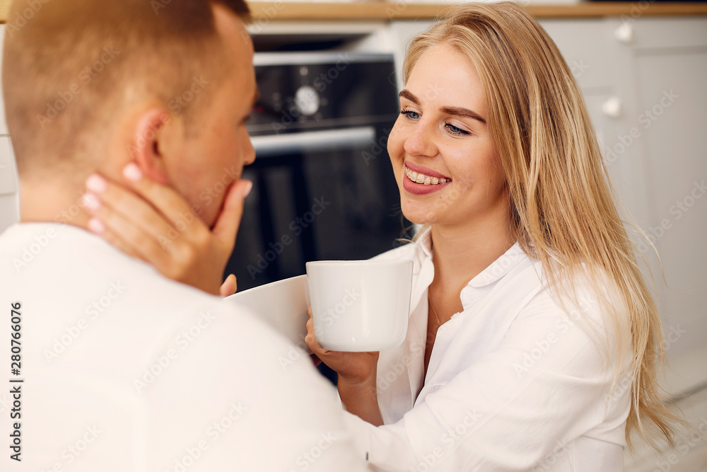 Cute couple in a kitchen. Lady in a white shirt. Pair at home Cute couple in a kitchen. Lady in a white shirt. Pair at home