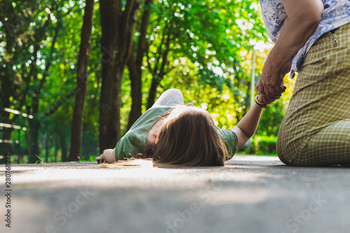 Fainted girl checked by an old woman – Teenager lying on the ground while pulse is checked by an elder citizen