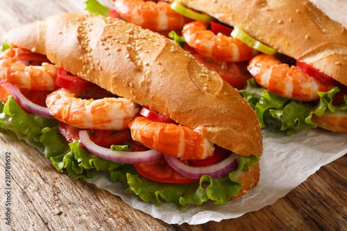 Delicious Sandwich with shrimps and fresh vegetables close-up on parchment. Horizontal