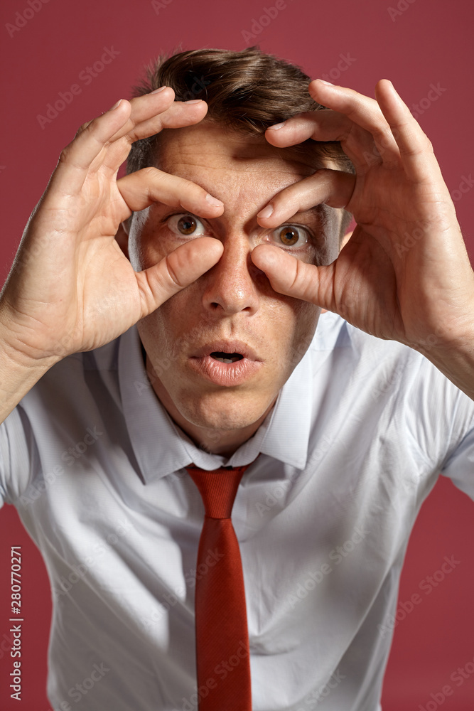 Portrait of a young brunet man posing in a studio against a red background. Portrait of a young brunet man posing in a studio against a red background.