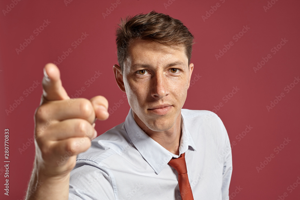 Portrait of a young brunet man posing in a studio against a red background. Portrait of a young brunet man posing in a studio against a red background.
