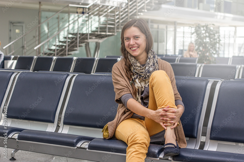 Happy smiling Woman waiting in airport seats. A woman traveler while sitting in the airport Happy smiling Woman waiting in airport seats. A woman traveler while sitting in the airport