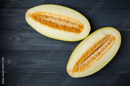 Fresh half of melon with seeds. On dark wooden background. Top view.