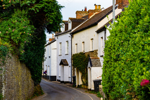 Narrow road with townhouses in British fish town framed in green hedges