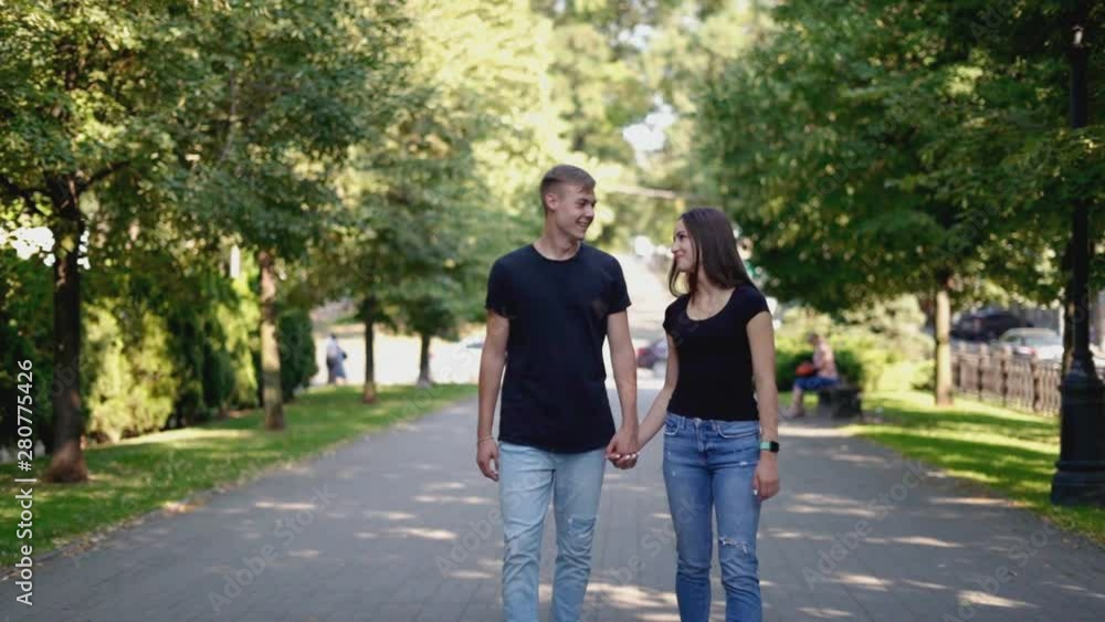 Cheerful, in love, happy couple walking along the alley in the city Cheerful, in love, happy couple walking along the alley in the city