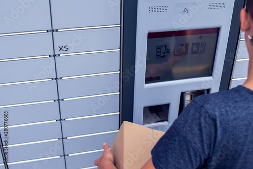 Client using automated self service post terminal machine or locker to deposit a parcel for storage photo